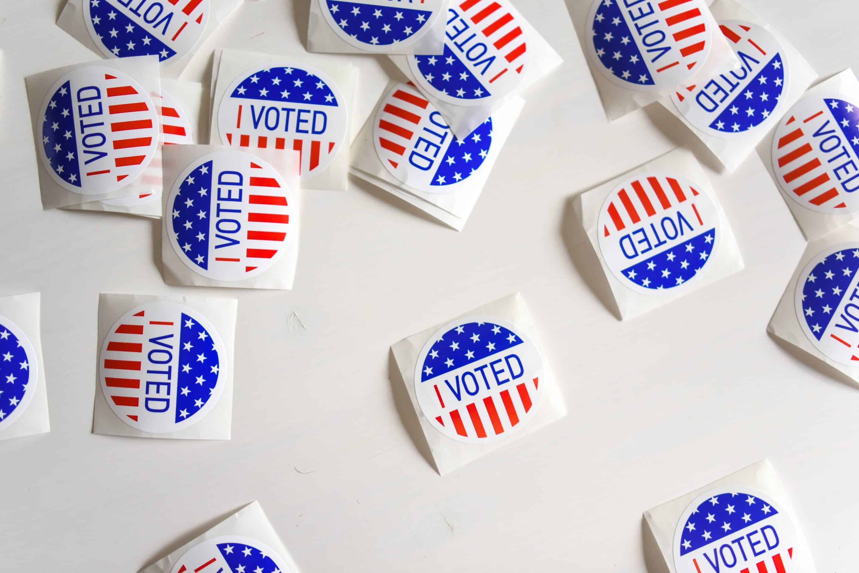 Red, white, and blue stickers with the words "I Voted" lay on a white surface