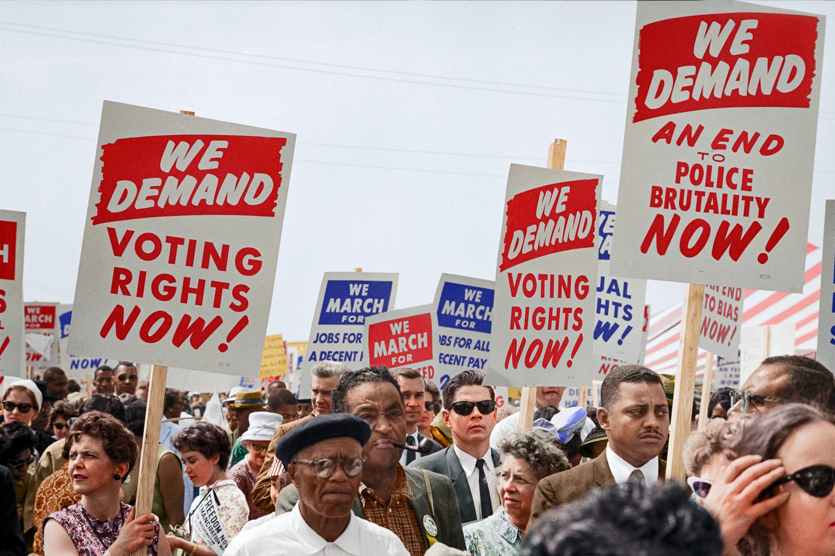 a crowd from the 1963 March on Washington hold signs that read "We demand voting rights now"