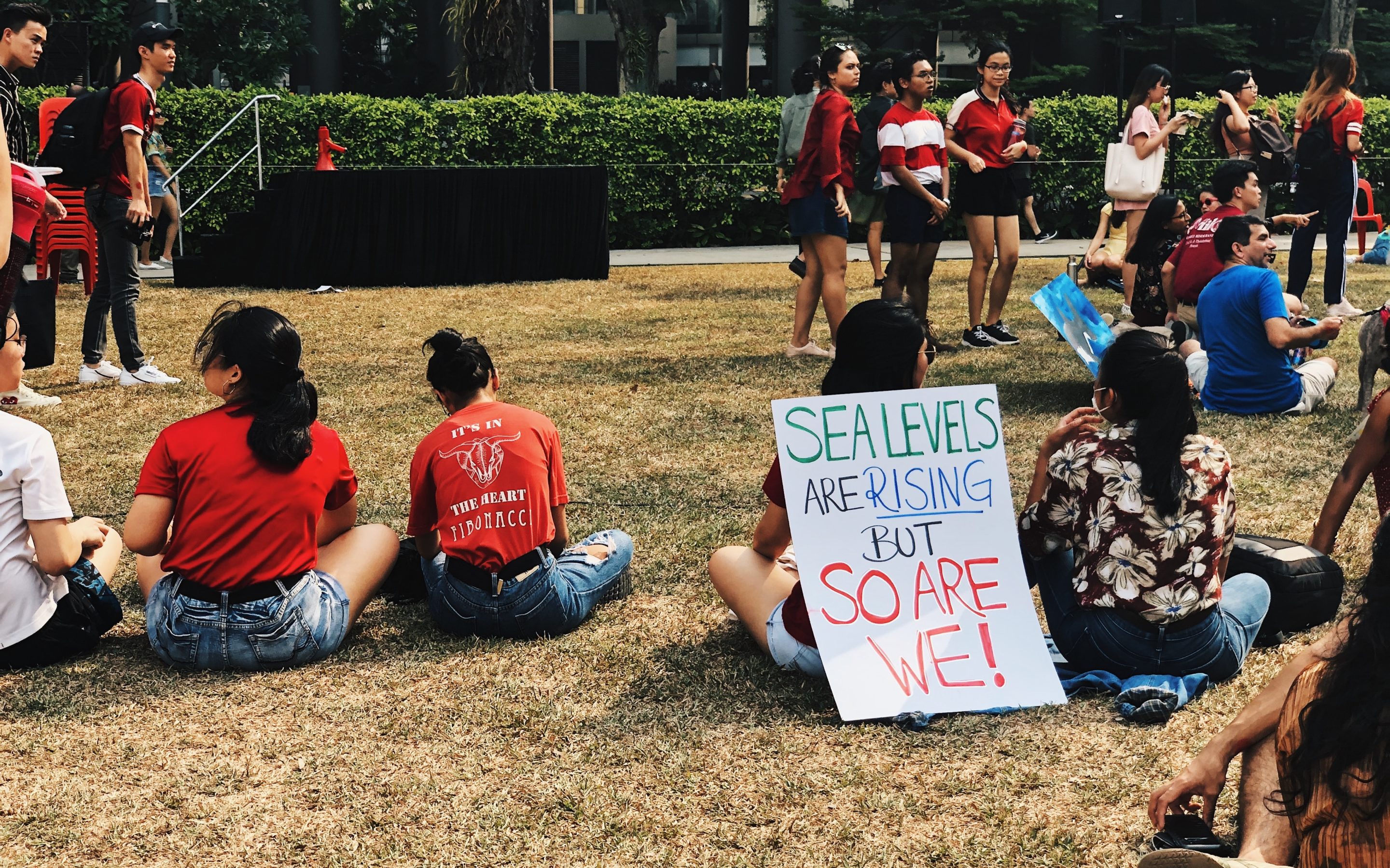 Activists sit at protests with sign that reads 'sea levels are rising, but so are we!'