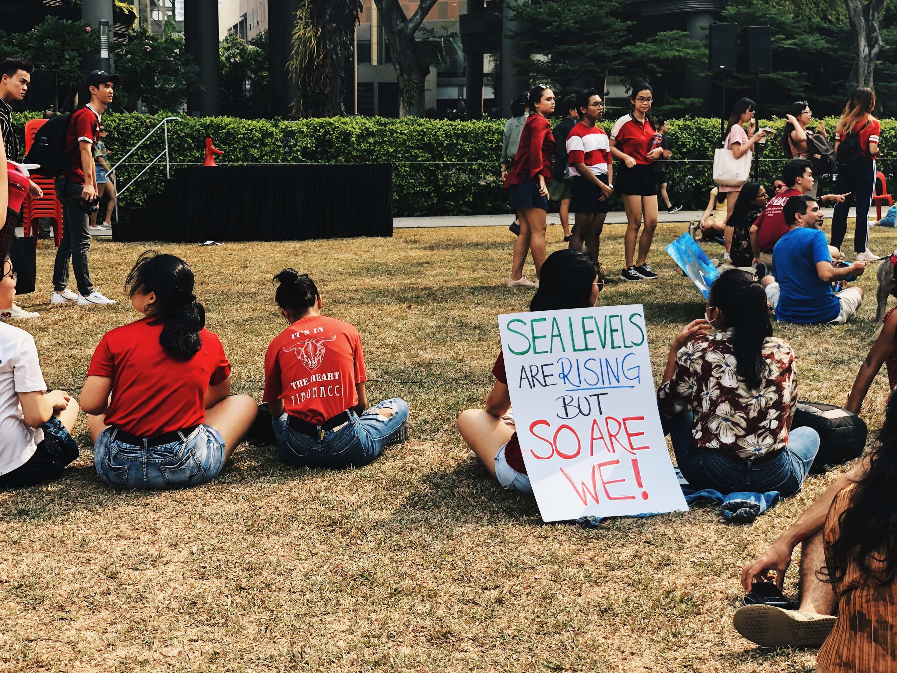 Activists sit at protests with sign that reads 'sea levels are rising, but so are we!'