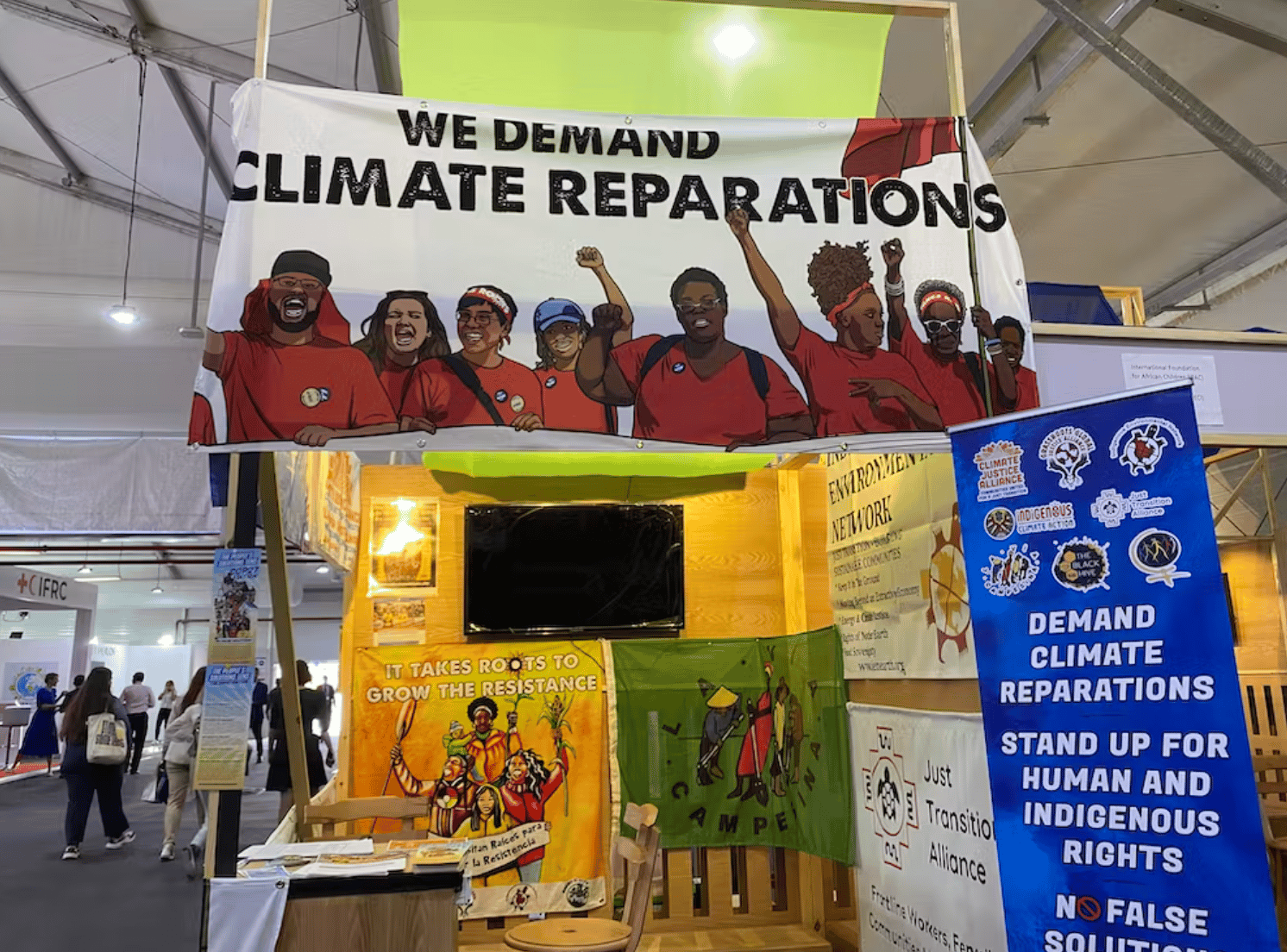 conference booth with signs reading, "we demand climate reparations"